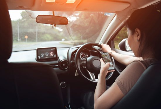 woman driving a car while holding phone along with DeliveryDart logo