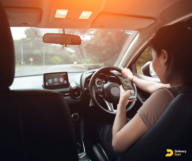 woman driving a car while holding phone along with DeliveryDart logo