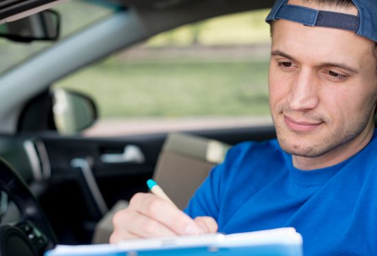 delivery driver sitting in a car filling forms with the DeliveryDart logo