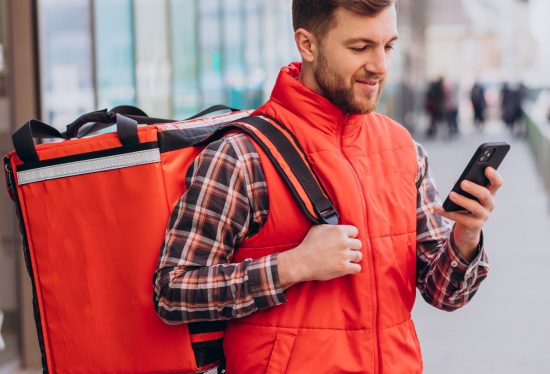 image of a delivery driver looking into his phone and smiling with DeliveryDart logo