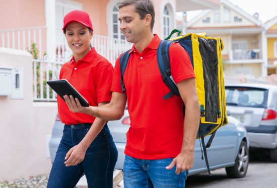 image of a male and female delivery driver walking while holding a device along with the DeliveryDart logo